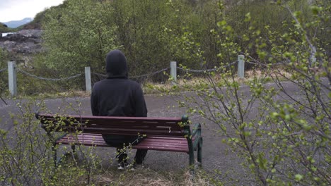 A-man-with-a-hoodie-sitting-alone-at-a-bench-lonely,-thinking-about-life