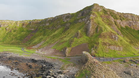 Aerial-trucking-shot-of-tourists-hiking-at-the-Causeway-Coast-in-Northern-Ireland