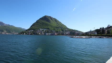 Panning-shot-of-the-beautiful-coastline-in-Lugano,-Switzerland-during-a-sunny-day-1