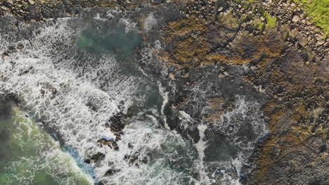 Static-top-down-view-of-oceanic-waves-crashing-at-the-rocky-shore-of-Northern-Ireland