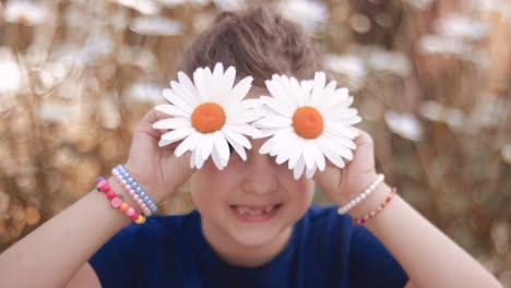Cute-little-girl-playing-with-Shasta-daisy-flowers,-making-faces,-having-fun
