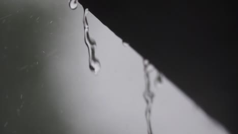 Slow-motion-droplets-fall-of-roof-in-windy-storm