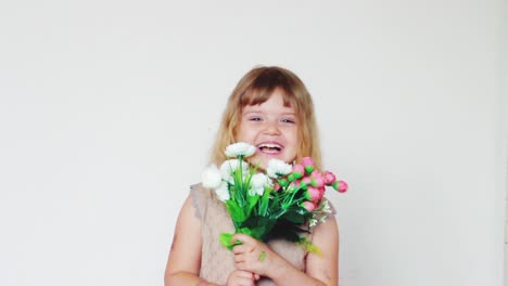 Entzückendes-Kleines-Mädchen-Mit-Künstlichem-Blumenstrauß,-Das-Es-Von-Ihrem-Gesicht-Wegbewegt-Und-Lacht,-In-Die-Kamera-Schaut