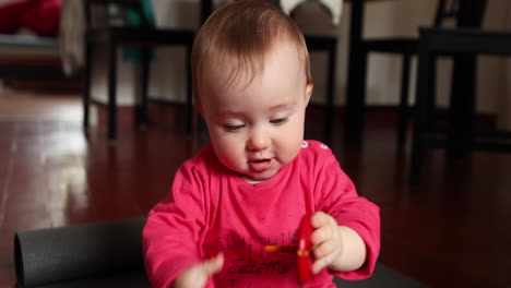 Fröhliches-Süßes-Kleines-Baby-Spielt-Vor-Der-Kamera-Mit-Einem-Holzspielzeug,-Aufgenommen-In-Zeitlupe