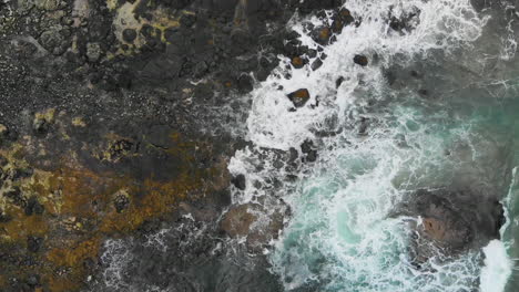 Top-down-flight-capturing-oceanic-waves-crashing-at-the-rocky-shore-of-Northern-Ireland