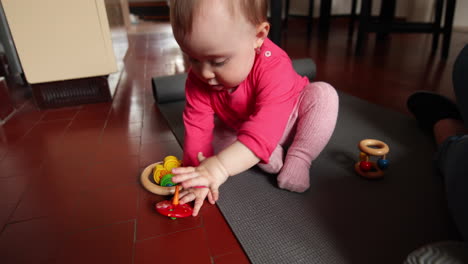 Cute-little-baby-plays-in-front-of-the-camera-with-a-wood-toy,-shot-in-slow-motion