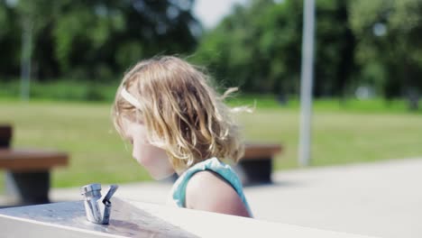 Cute-little-girl-drinking-water-from-a-drinking-fountain-on-a-hot-summer-day