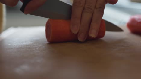 Closeup-of-woman-in-a-kitchen-using-a-sharp-knife-to-slice-a-carrot-into-pieces-1