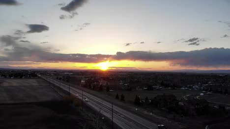 Drone-shot-of-sunset-over-the-highway-near-a-small-town