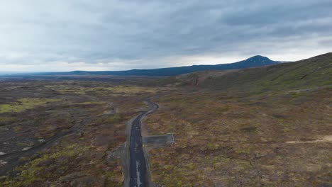Luftaufnahme-über-Eine-Schotterstraße-Im-Isländischen-Hochland,-Die-Die-Epische-Landschaft-Und-Einige-Majestätische-Berge-Im-Hintergrund-Zeigt-1