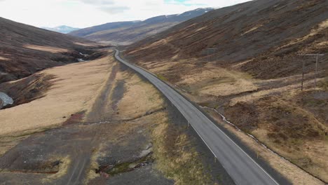 Aerial-footage-of-two-cars-driving-at-the-Icelandic-highway-located-up-in-the-mountains-of-Iceland