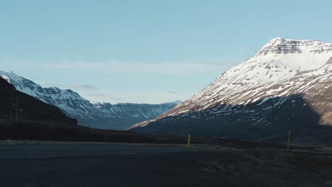 Panning-from-left-to-right-showing-snow-covered-mountains-and-a-road-in-Iceland-close-to-Seydisfjordur