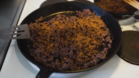 Putting-taco-spice-on-some-ground-beef-laying-in-a-hot-cast-iron