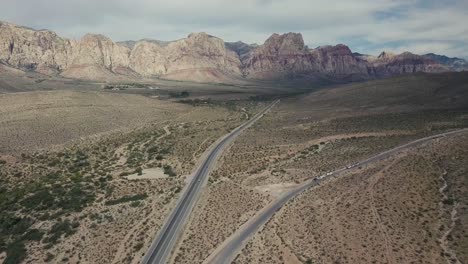 Fliegen-Entlang-Der-Straße-In-Der-Wüste-Von-Nevada-Mit-Bergen-Im-Hintergrund