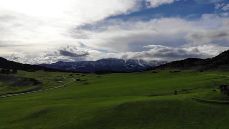 Beautiful-rising-drone-shot-over-green-pastures-and-snowy-mountains