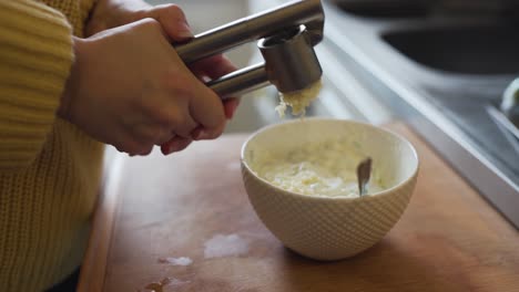 Pressing-some-fresh-garlic-into-a-bowl-of-grated-cucumber-and-greek-yogurt