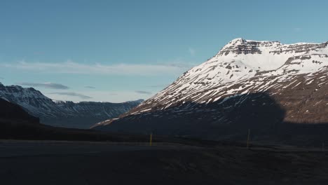 Panorámica-De-Izquierda-A-Derecha-Que-Muestra-Montañas-Cubiertas-De-Nieve-Y-Una-Carretera-En-Islandia-Cerca-De-Seydisfjordur-1