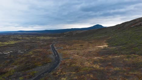 Aerial-view-over-gravel-road-located-in-the-icelandic-highlands-showing-the-epic-landscape-and-some-majestic-mountains-in-the-background