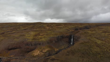 Aerial-footage-moving-towards-a-waterfall-located-in-the-highlands-up-in-the-mountains-of-Iceland