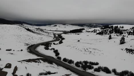Drone-shot-of-country-road-running-through-the-mountains-during-winter