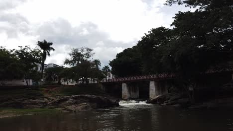 Panning-shot-of-the-outdoors,-bridge,-and-small-waterfall-in-Pirenopolis,-Brazil
