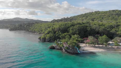 Cinematic-aerial-drone-shot-of-iconic-resort-in-philippines-island,-with-crystal-clear-blue-water,-white-sand-and-cliff-jumping-on-hot-sunny-summer-day