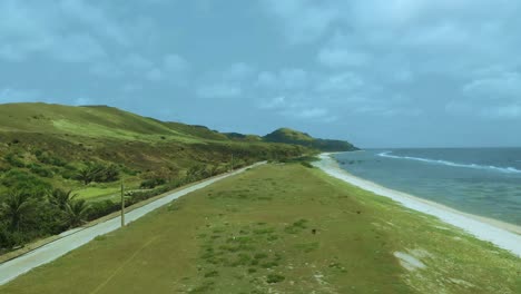 A-drone-shot-of-green-fields-near-the-sea-in-Sabtang,-Batanes