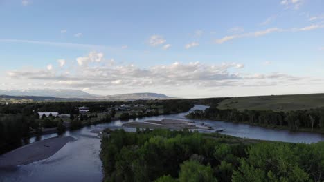 Ariel-shot-of-a-small-town,-a-river-and-the-mountains-in-the-distance