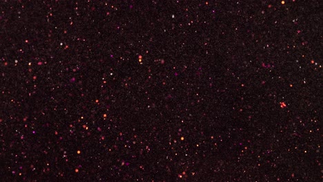 In-Zeitlupe-Bewegen-Sich-Rosa-Und-Goldene-Glitzerpartikel-Fast-Zufällig-Vor-Einem-Schwarzen-Hintergrund