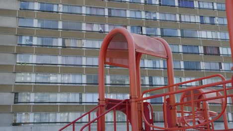 Cinematic-shot-of-an-empty-red-playhouse-in-front-of-an-old-apartment-block