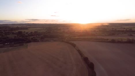Slowly-flying-towards-the-sunset,-passing-over-rolling-fields-and-farmland