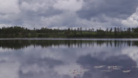 Regenwolken-über-Einem-Schwedischen-See-In-Einem-Wald,-Wobei-Das-Wasser-Eine-Spiegelreflexion-Im-Wasser-Der-Wolken-Und-Bäume-Erzeugt