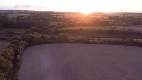 Flying-across-beautiful-rolling-fields-away-a-stunning-orange-sunset