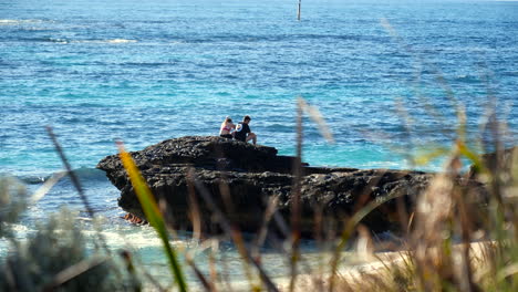 Lovers-sitting-on-rocks-next-to-the-ocean