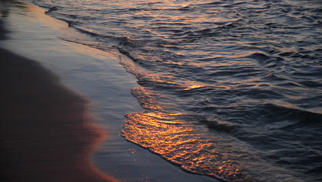 Waves-lightly-crashing-on-beach-during-sunset