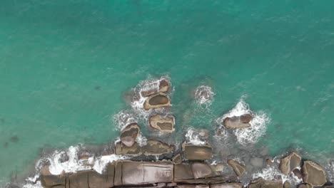 Aerial-view-of-ocean-waves-crashing-on-the-rock-bay