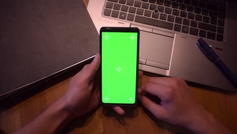 Young-adult-boy-hold-smartphone-with-a-greenscreen-in-his-hands-5