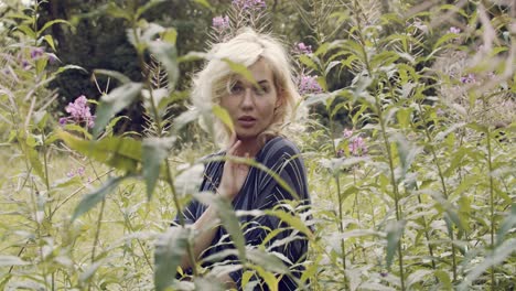 Dreamy,-voyeuristic-shot-of-a-seductive-blonde-woman-posing-in-a-field-of-wild-flowers