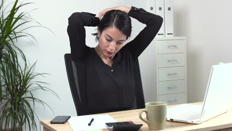 Atractive-Female-office-worker-tying-hair-up-at-the-desk