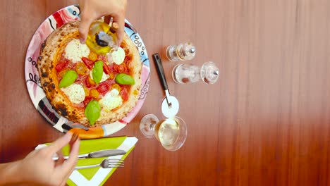 Vertikales-Video-Von-Händen,-Die-Olivenöl-Auf-Eine-Schön-Aussehende-Frische-Italienische-Pizza-Gießen