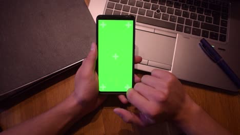 Young-adult-boy-hold-smartphone-with-a-greenscreen-in-his-hands-2