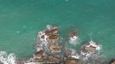 Aerial-view-of-ocean-waves-crashing-on-the-rock-bay-1