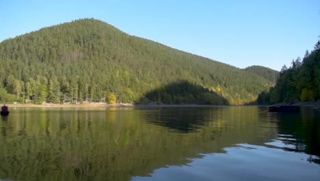 Entspannender-Blick-Auf-Einen-Großen-See-Mit-Reflexion-über-Das-Wasser-Und-Die-Hügel-Im-Hintergrund-Im-Herbst