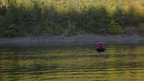 Small-boat-is-driving-by-in-the-background-and-a-buoy-is-floating-in-the-foreground-at-the-local-reservoir