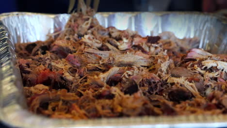 Close-up-of-a-fork-being-stabbed-into-an-aluminum-tray-of-smoked-seasoned-pulled-pork