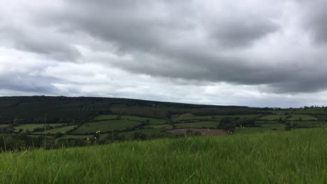 A-low-down-timelapse-of-dark-clouds-rolling-over-beautiful-green-fields