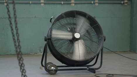 Industrial-chain-swinging-in-front-of-a-big-spinning-fan