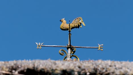 Iron-Rooster-Weather-Vane-with-Compass-on-top-of-Thatched-Roof