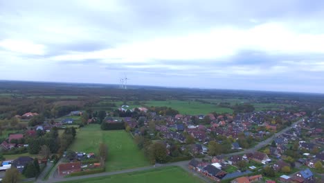 Aerial-drone-shot-of-a-village-in-East-Frisia,-Germany-with-windmills-in-background