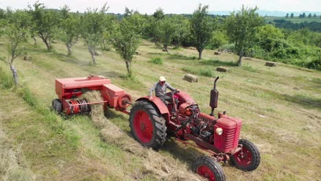 Aerial-of-a-farmer-with-a-tractor-carrying-a-hay-baler-through-a-field